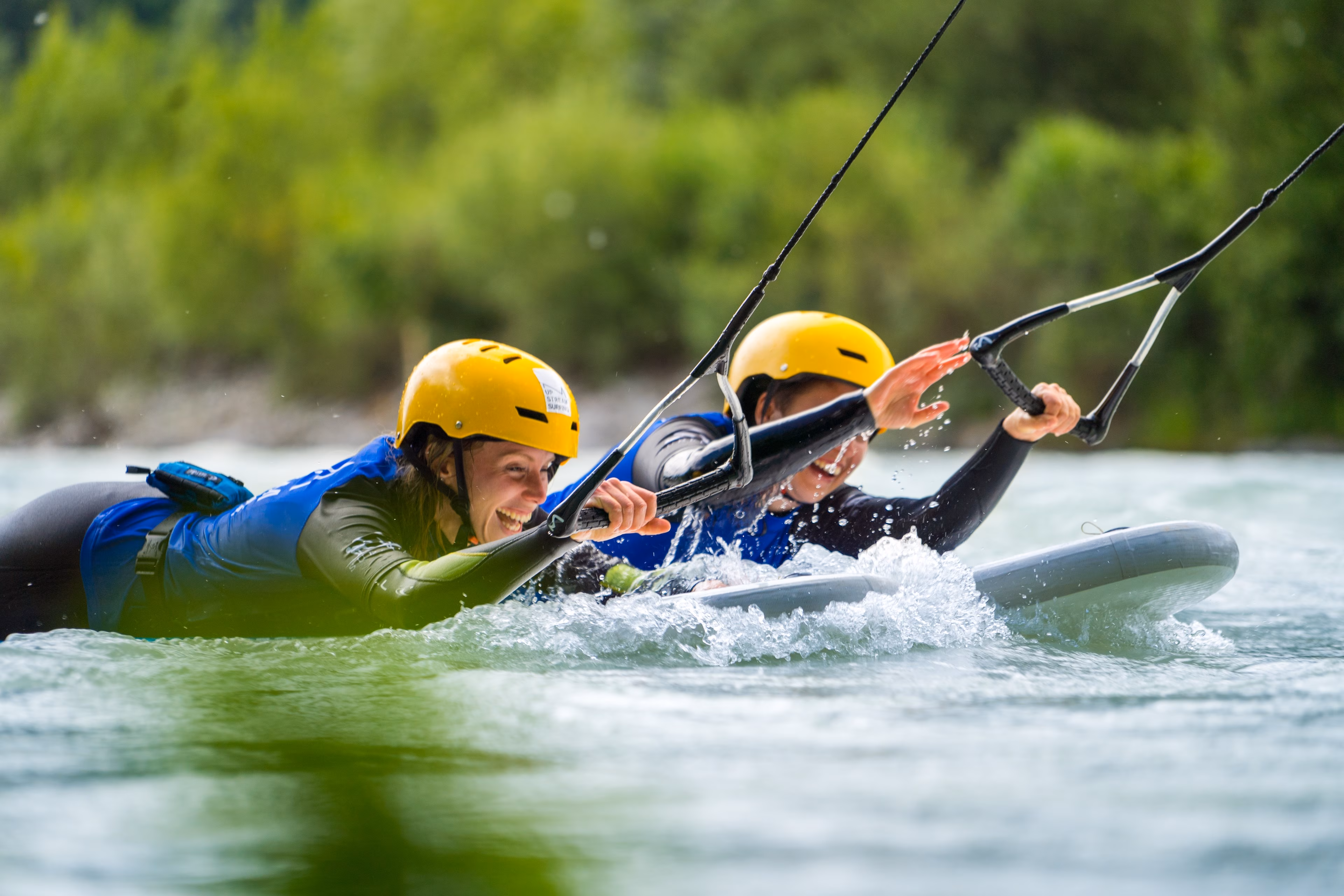 Zwei Menschen liegen beim Upstream-Surfing bäuchlings auf Surfbrettern