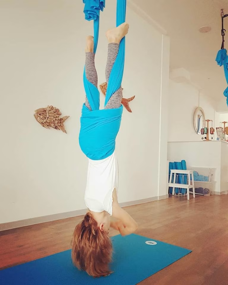 Ein Kind hängt kopfüber in einem Aerial-Yoga-Tuch