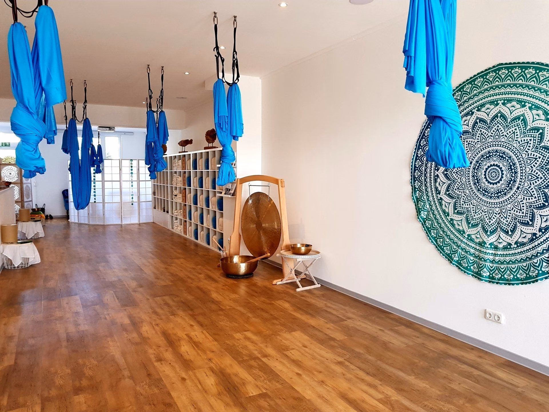 In einem Raum hängen blaue Aerial-Yoga-Tücher von der Decke