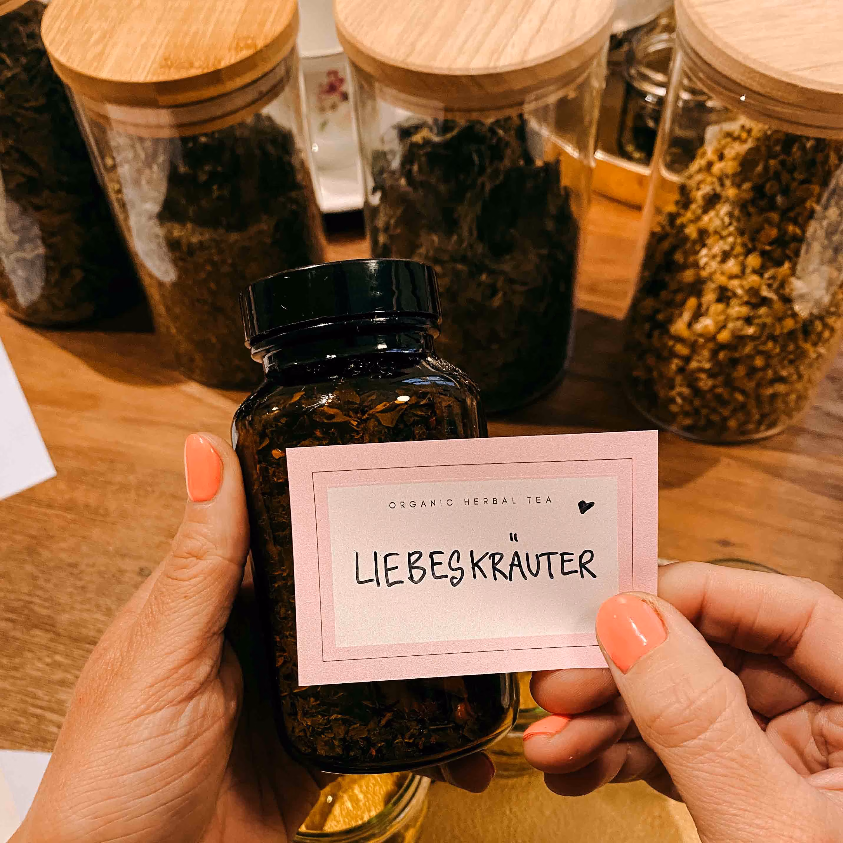 Eine Person klebt ein Etikett auf ihren selbstgemachten Kräutertee