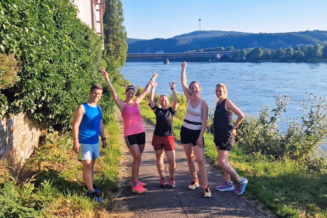 Running City Tour am Fluss: Jogging-Stadtführung mit sportlicher Gruppe und Ausblick auf die Natur.