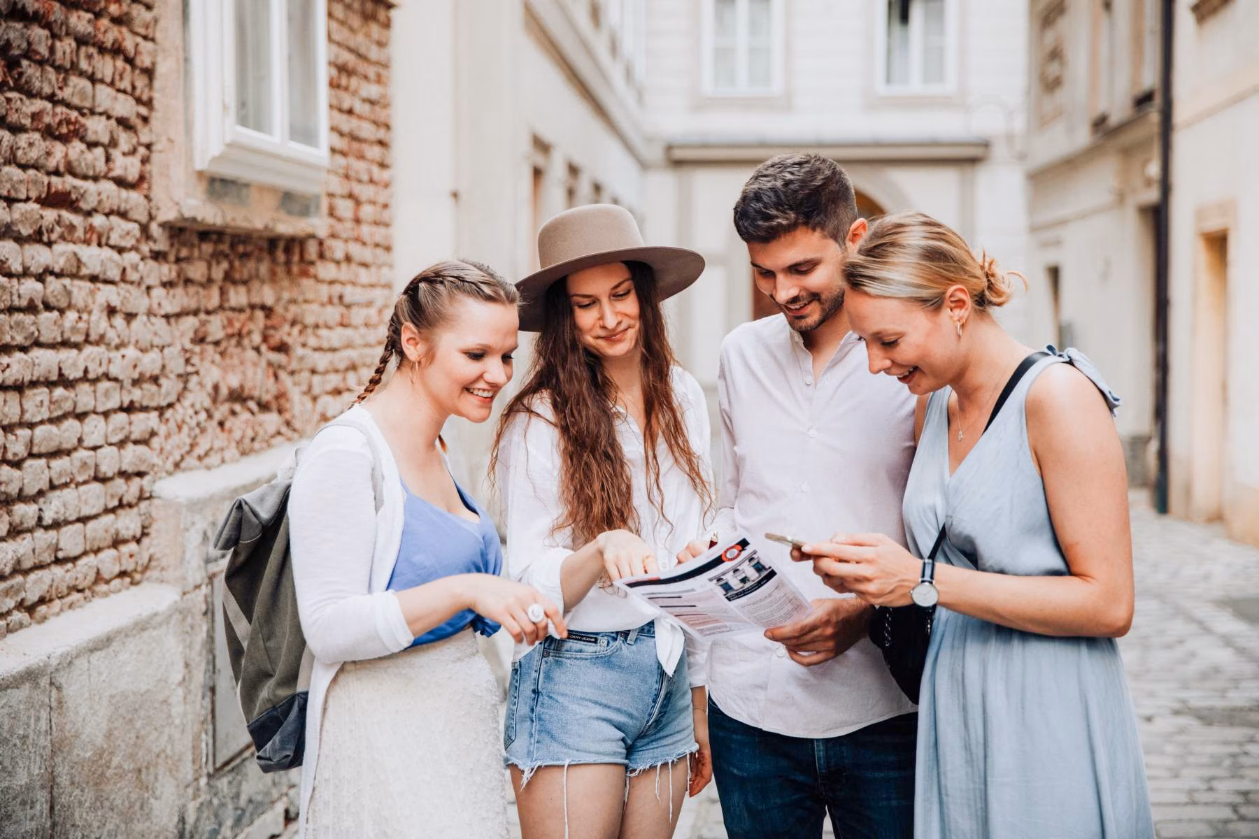 Vier fröhlich aussehende Personen schauen während einer selbstgeführten Krimi-Stadtführung auf die ausgedruckte Spielanleitung