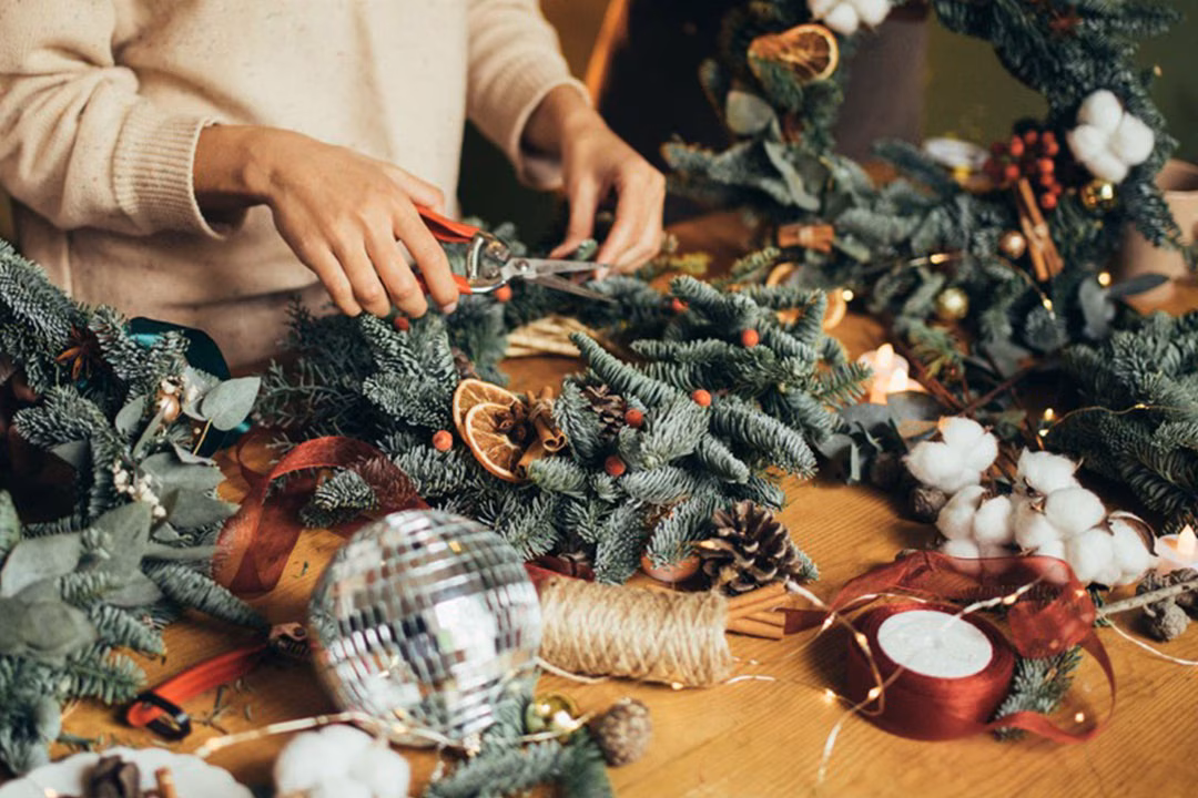 Eine Person dekoriert einen Adventskranz DIY-Workshop: Adventskranz binden in Lübeck.