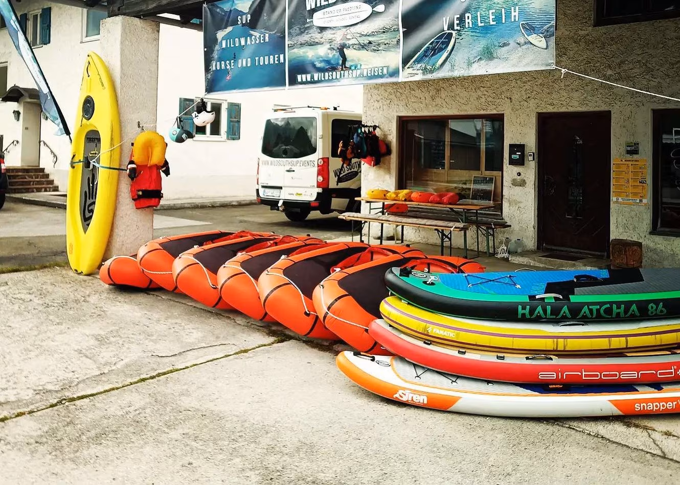 Mehrere Packrafts und SUP-Boards vor einem Verleih