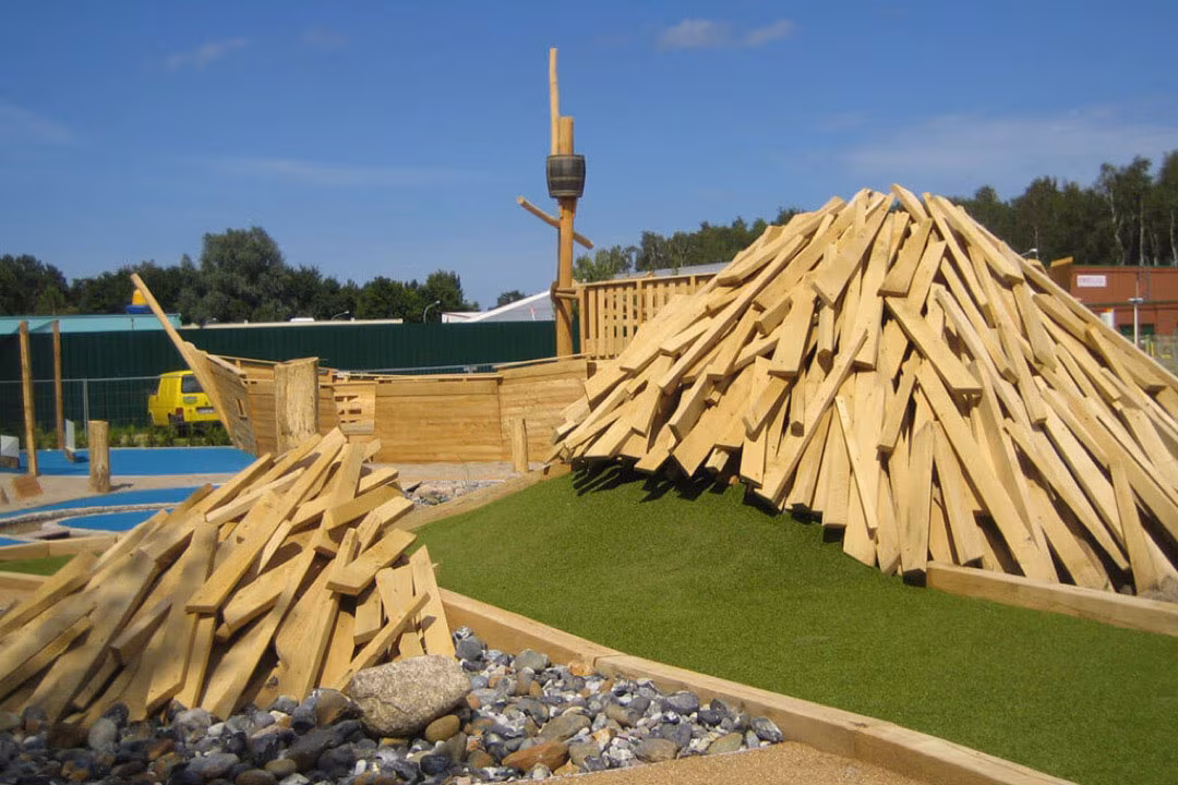 Ein Vulkan aus Holzscheiten auf der 
Minigolf-Anlage Piraten der Ostsee, durch den Minigolf-Spieler hindurch spielen müssen.