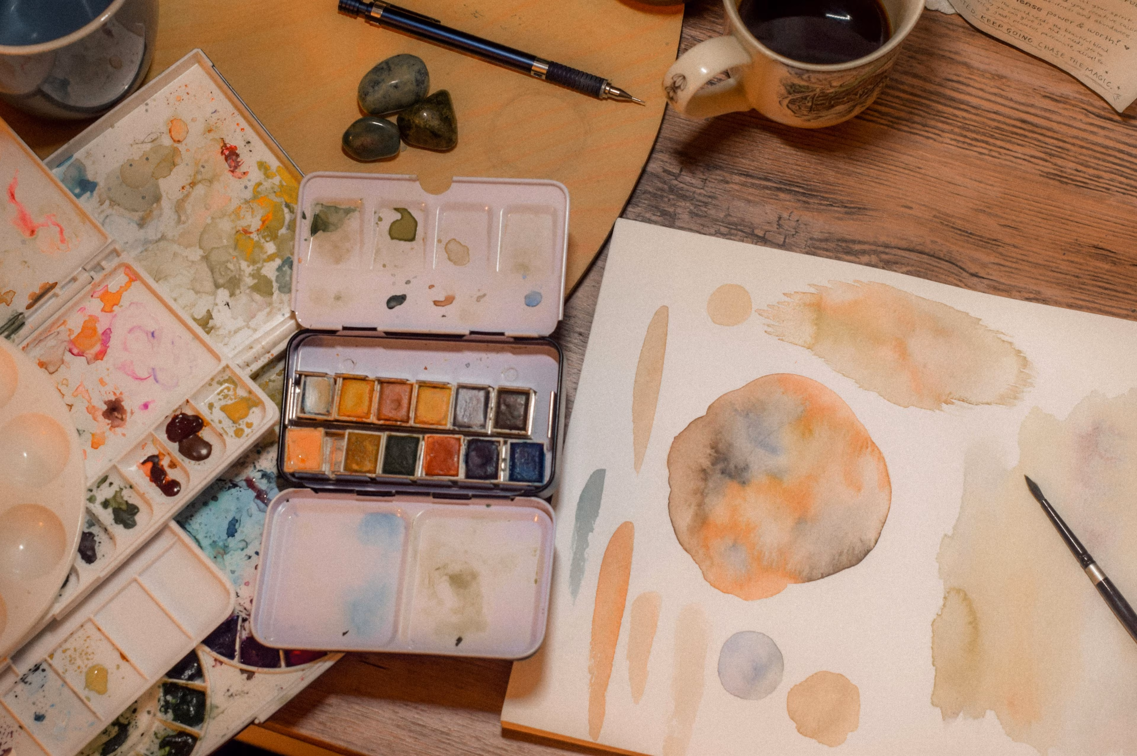 Aquarell-Farben und bemalte Blätter auf einem Tisch