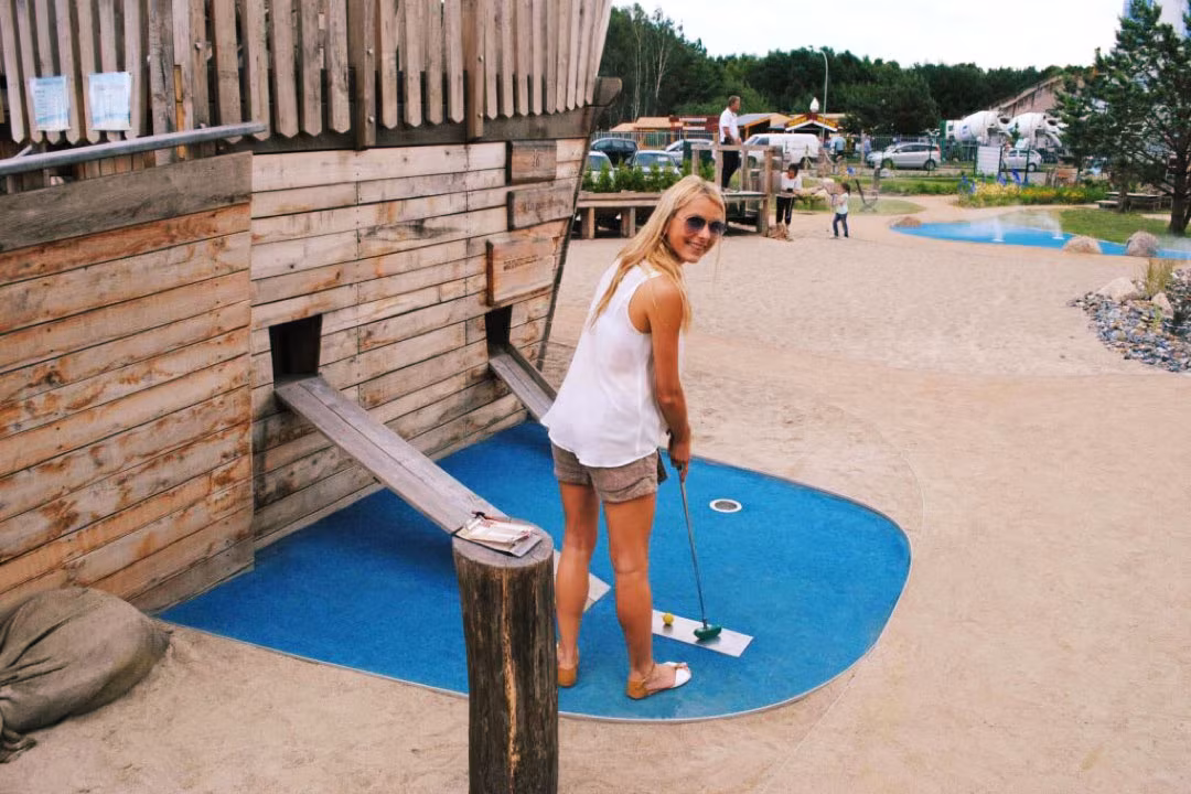 Eine Spielerin vor dem Piratenschiff mit Schläger in der Hand auf der Minigolf-Anlage Piraten der Ostsee.