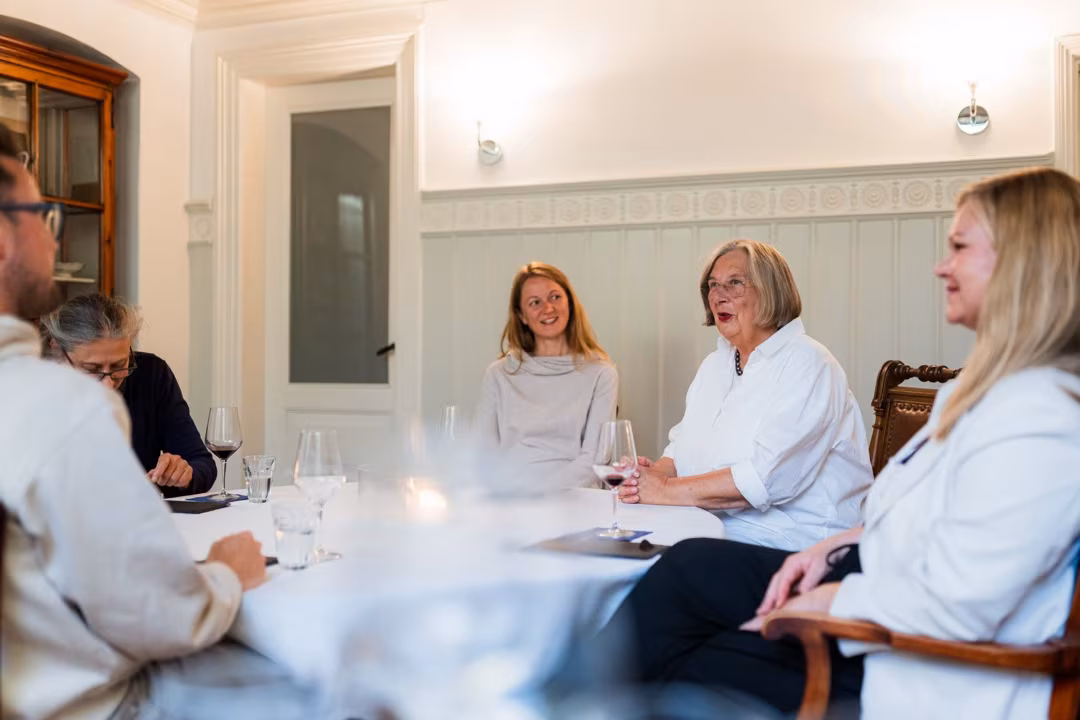 Menschen sitzen an einem Tisch in einem hellen, getäfelten Raum in Lübeck.