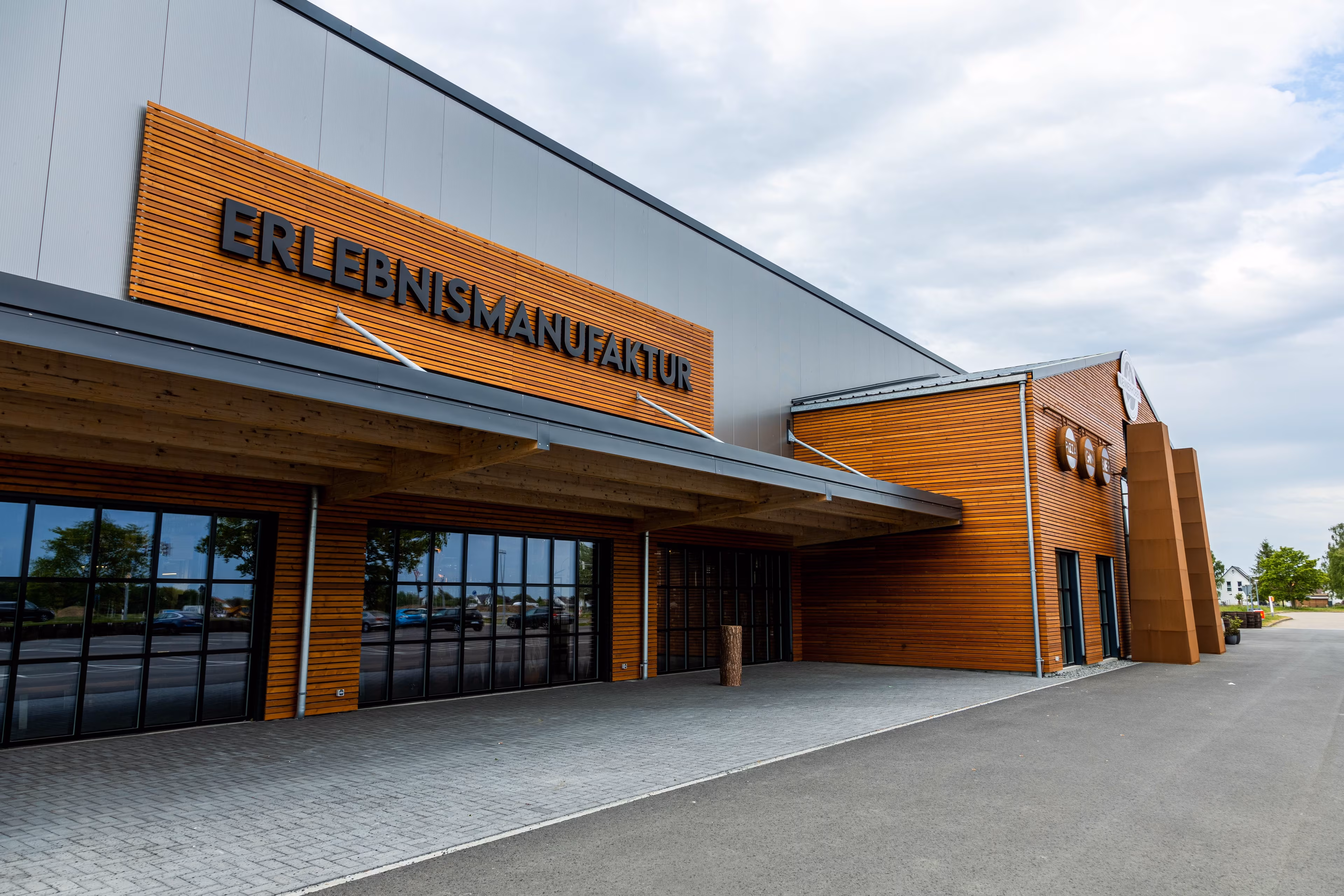 Eine teils mit Holz verkleidetet Gebäudefassade und dem Schriftzug Erlebnismanufaktur