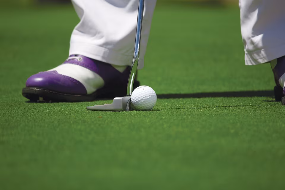 Eine Person mit lilafarbenen Golfschuhen beim Putten