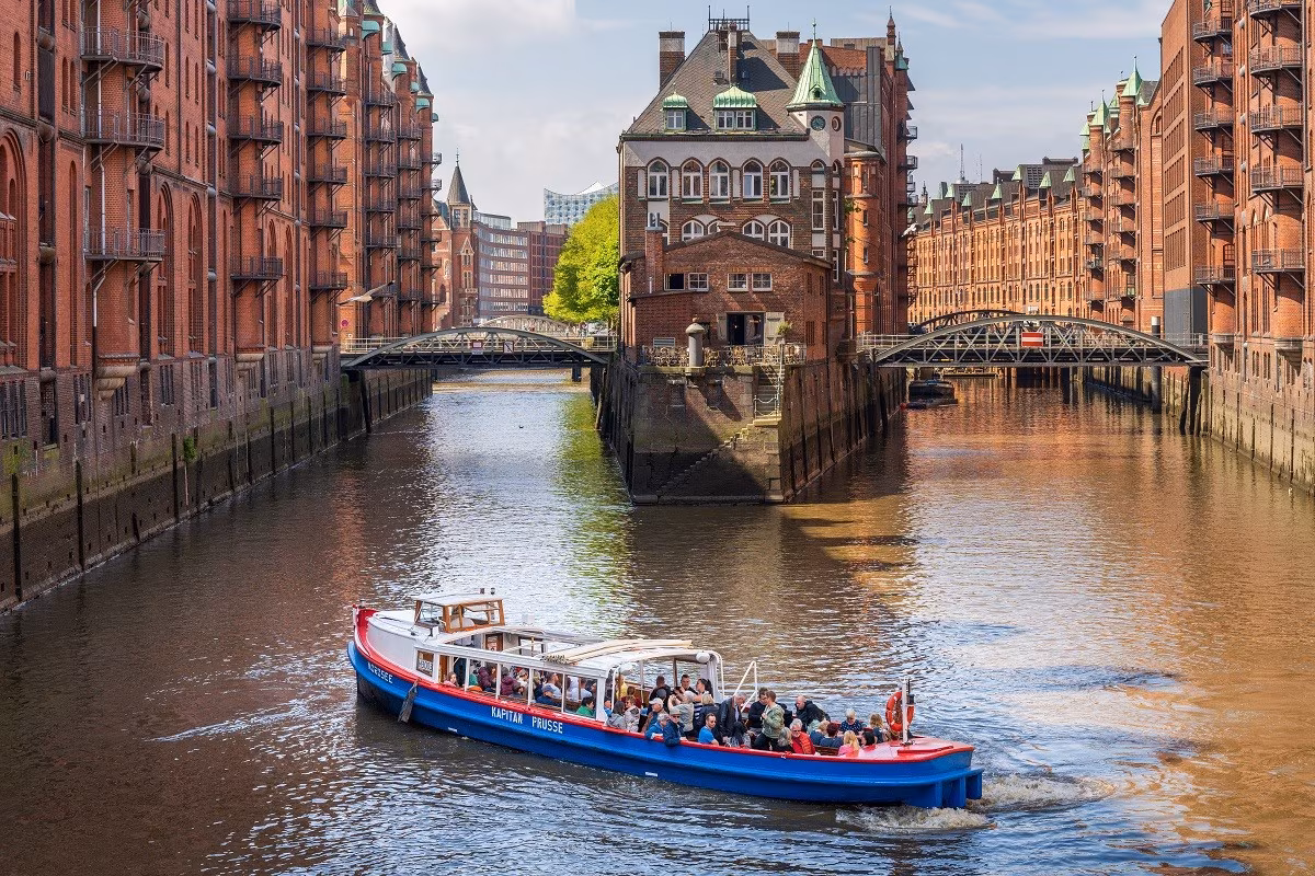 Eine blau-rote Barkasse der Schifffahrtsgesellschaft Kapitän Prüsse vor dem Wasserschloss in der Hamburger Speicherstadt