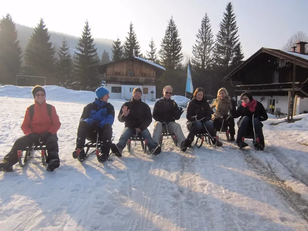 Eine Gruppe sitzt auf Schlitten beim Rodeln im Chiemgau