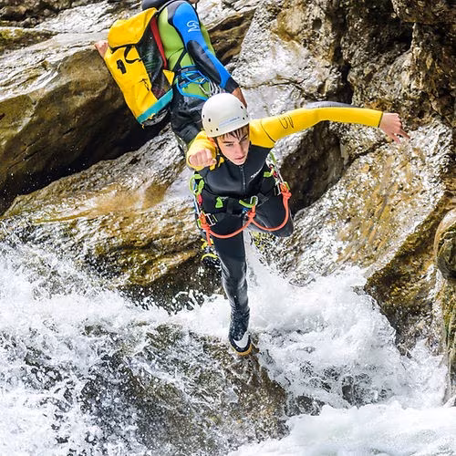 Eine Person springt beim Canyoning in der Starzlachklamm von einem Felsen