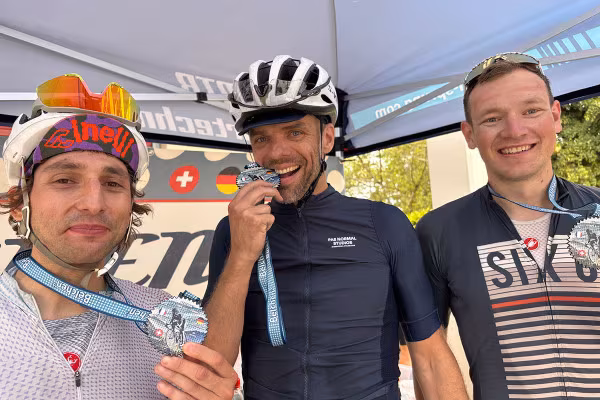 Finisher des Ultra-Distanz-Rennrad-Marathon, drei lächelnde Männer mit Medallien.