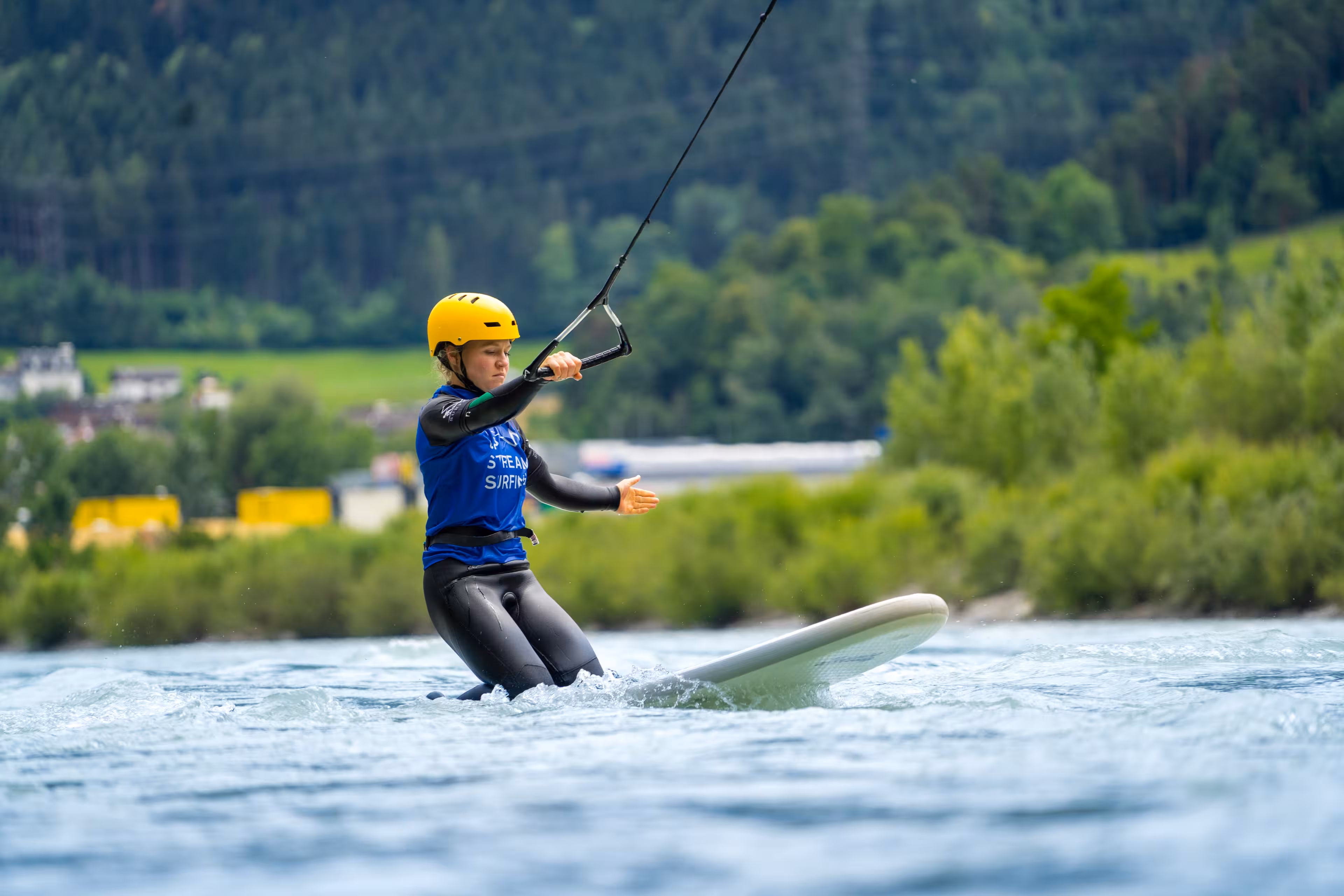 Eine Frau kniet beim Upstream-Surfing auf einem Surfbrett auf dem Inn