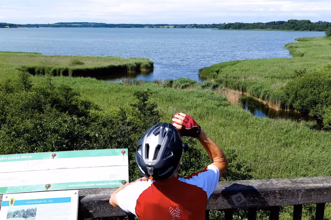 Rad-Guide Martin macht Rast an einem See und trinkt aus seiner Trinkflasche.