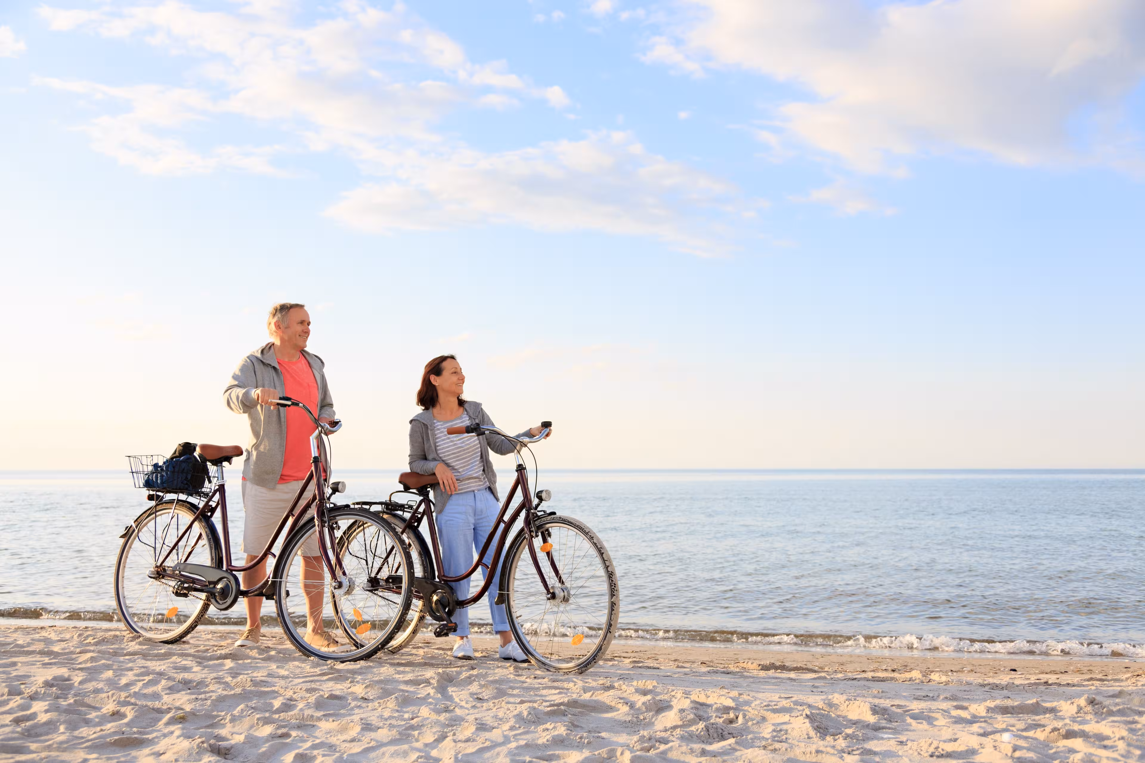 Ein Mann und eine Frau stehen neben ihren Fahrrädern am Strand