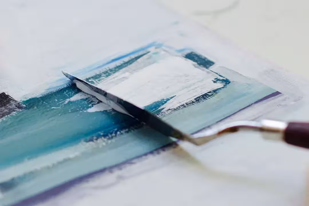 Ein Spachtel auf blauer Farbe mit weißen Elementen bei der ArtNight.