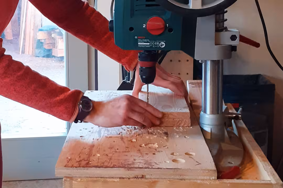 Teilnehmerin beim Mädelsabend in der Holzwerkstatt: Sie bohrt präzise Löcher in ein Holzbrett mit der Ständerbohrmaschine.