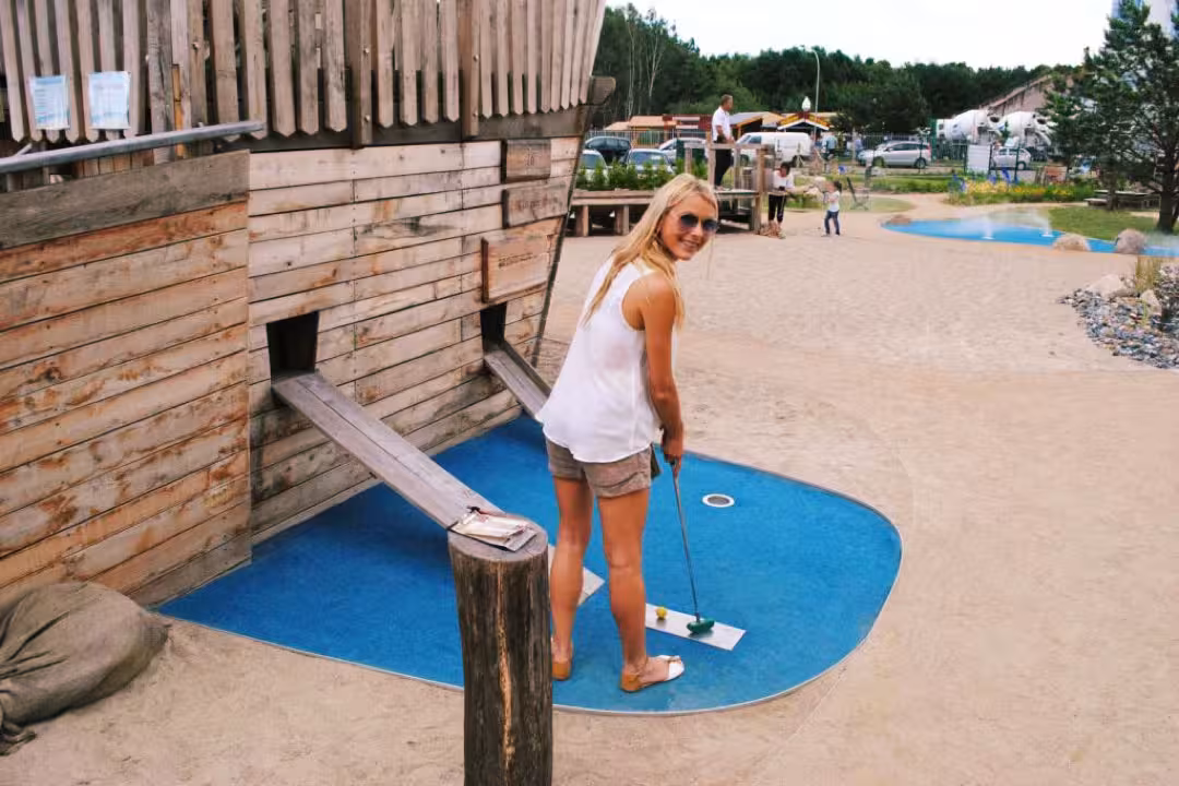 Eine Spielerin vor dem Piratenschiff mit Schläger in der Hand auf der Minigolf-Anlage Piraten der Ostsee.