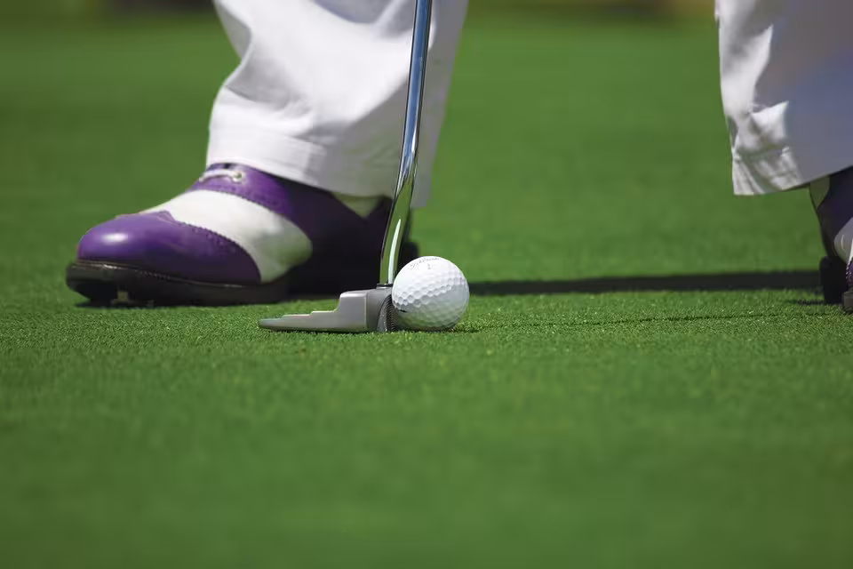 Eine Person mit lilafarbenen Golfschuhen beim Putten