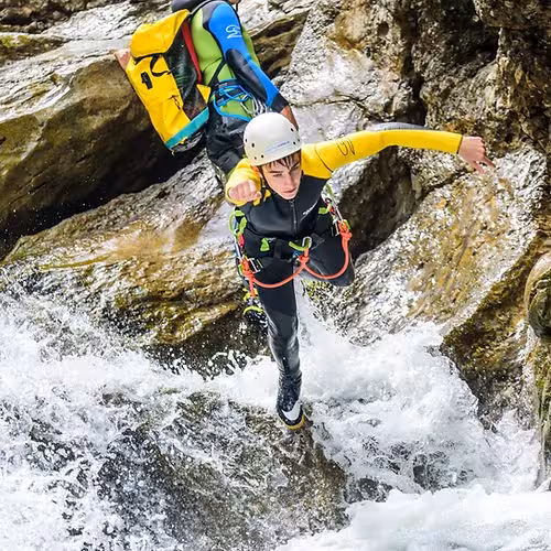 Eine Person springt beim Canyoning in der Starzlachklamm von einem Felsen