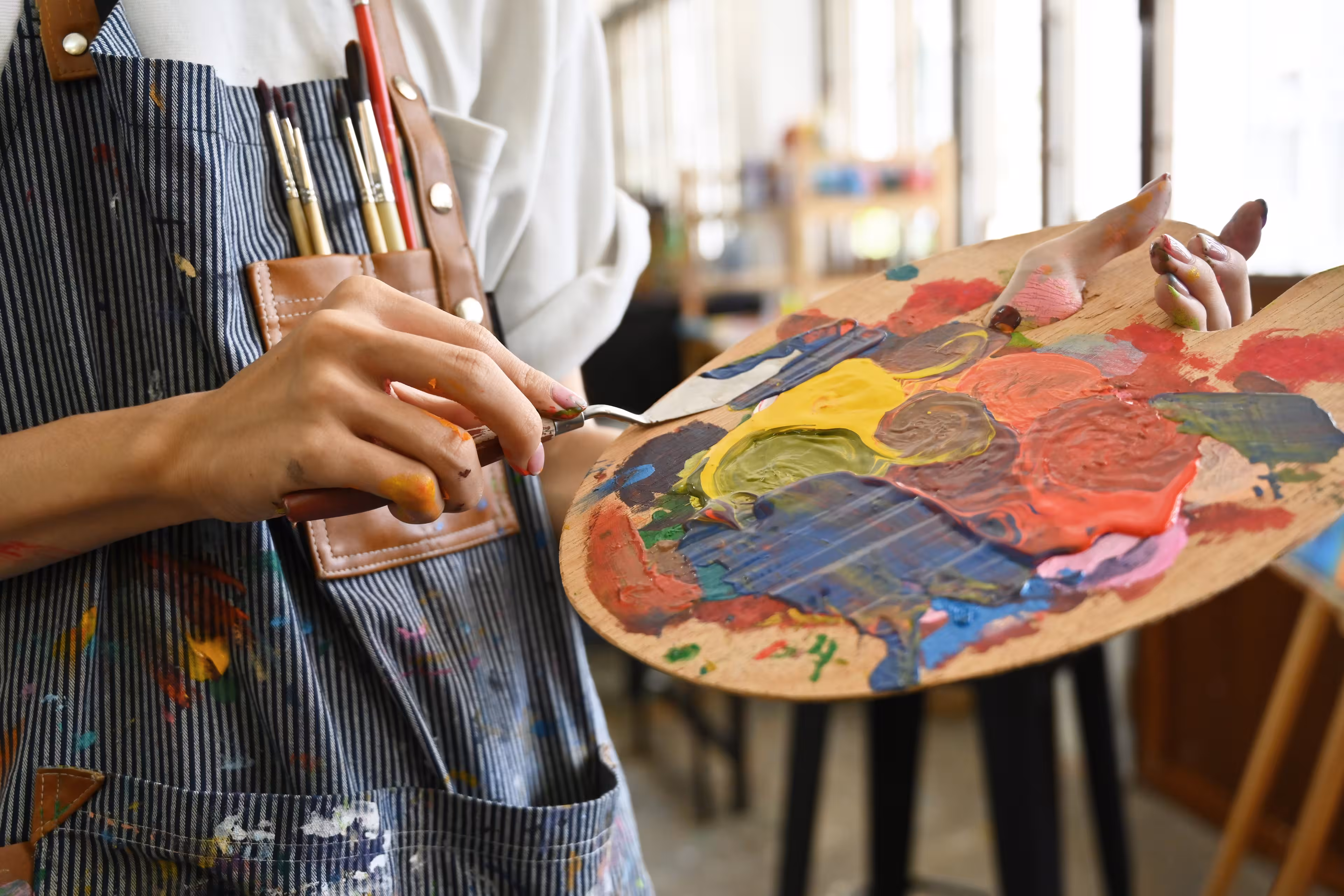 Eine Person mischt Acrylfarben auf einer Palette