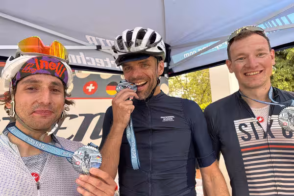 Finisher des Ultra-Distanz-Rennrad-Marathon, drei lächelnde Männer mit Medallien.
