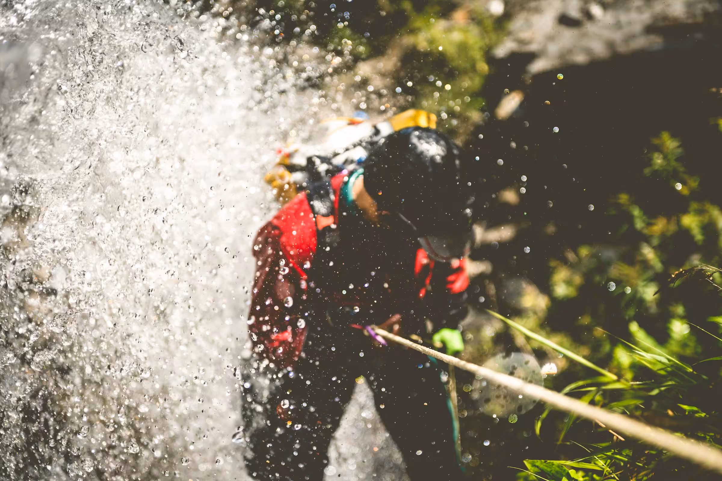 Eine Person seilt sich beim Canyoning durch einen Wasserfall ab