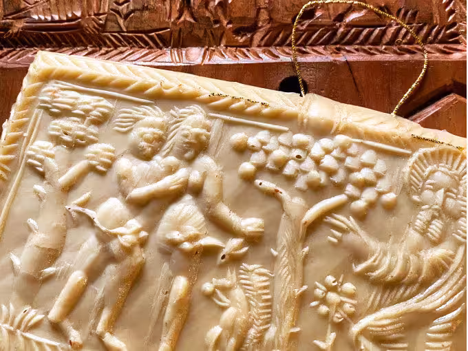 Alte Lebkuchenform aus Holz mit kunstvollen Verzierungen, die sich auf das Lebkuchengebäck davor abgedrückt haben.