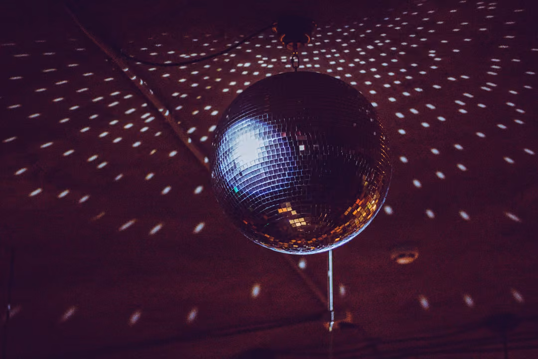Silvesterparty in Bottrop: Große Diskokugel an einer Decke, die Licht reflektiert.
