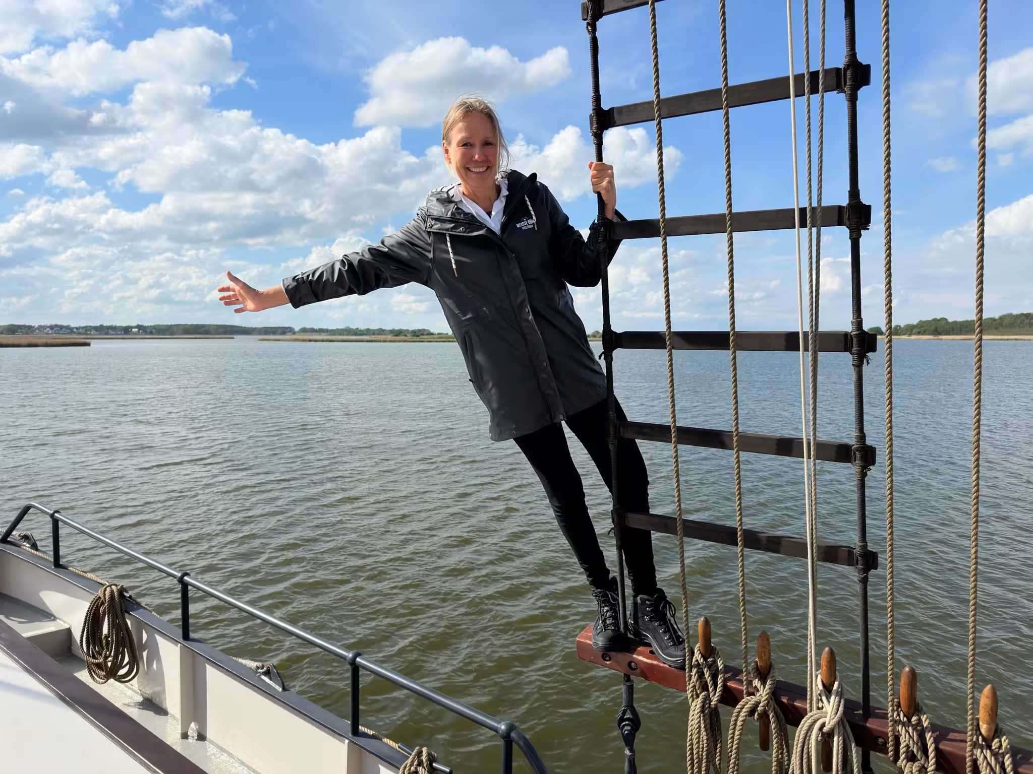 Eine Person, die bei einem Segeltörn in der Takelage des Segelschiffs „Weisse Düne“ hängt